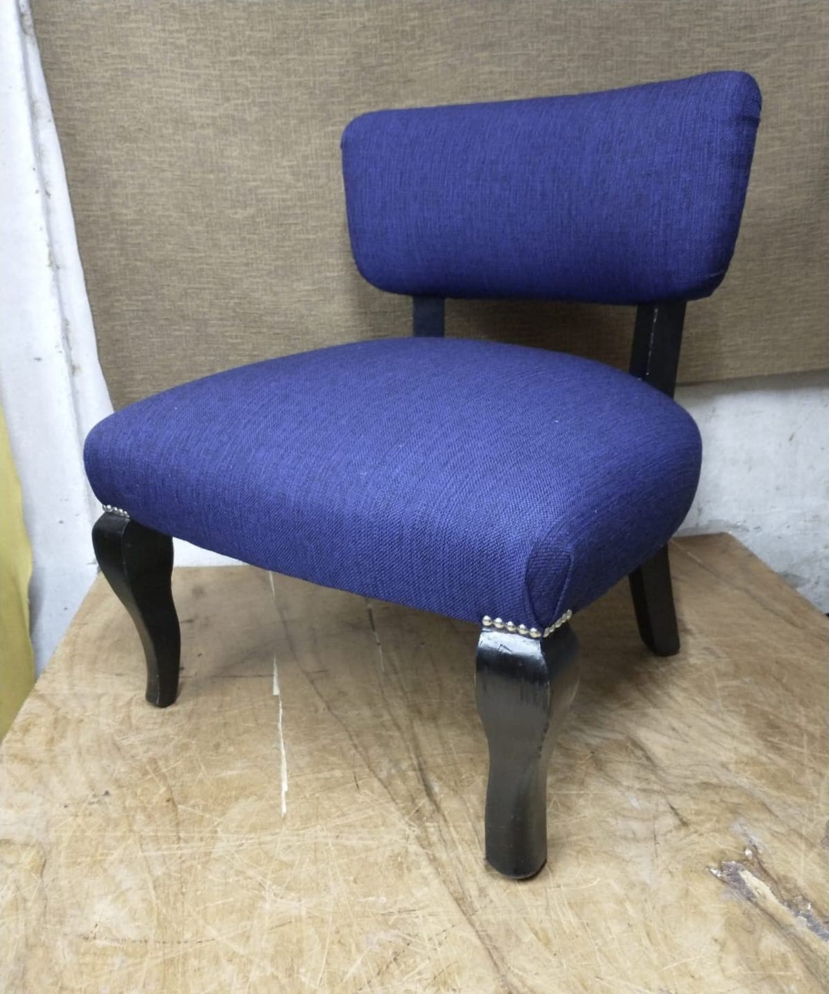Silla baja tapizada en tela azul, con tachas y patas cabriolé