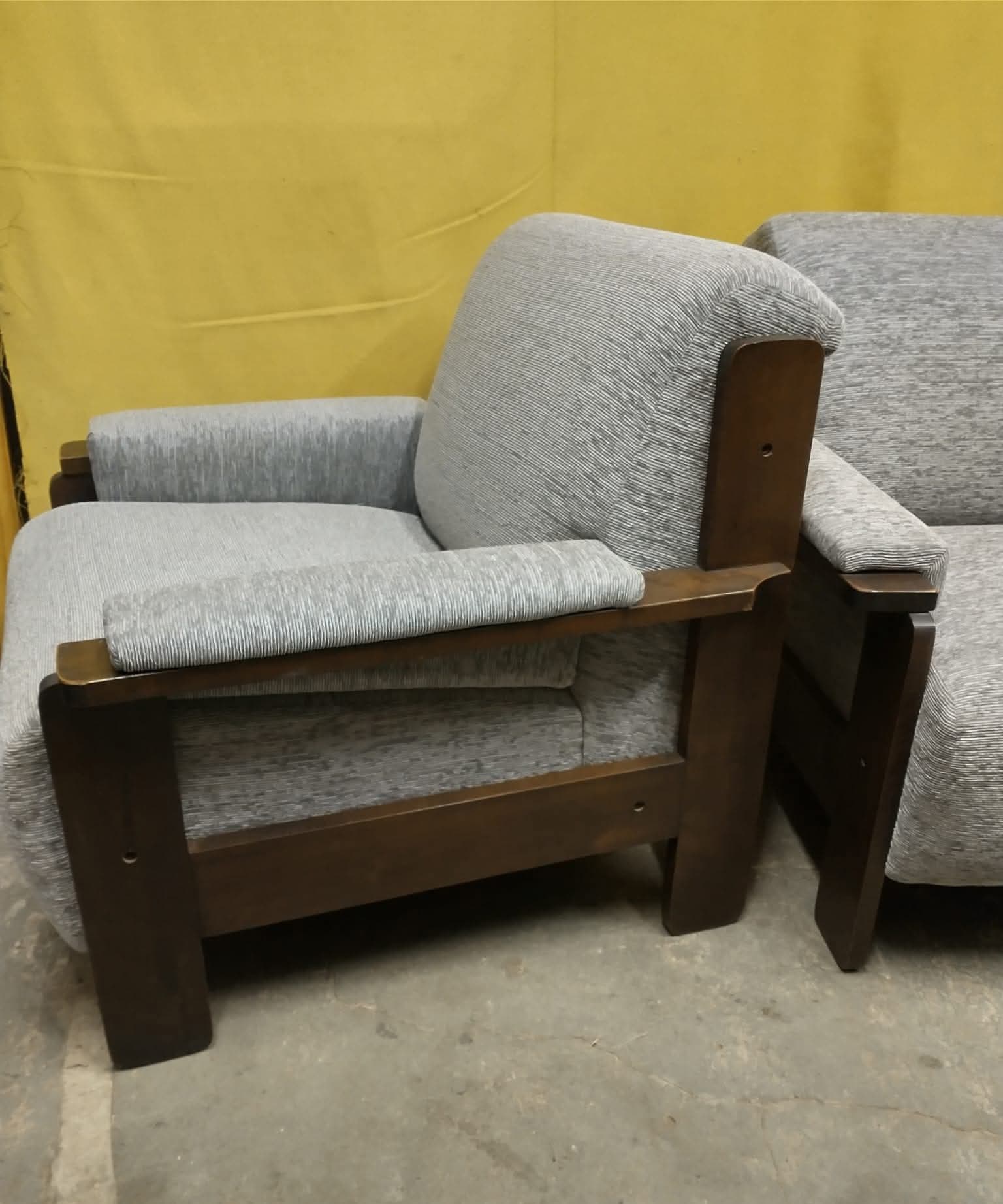 Sillón de madera oscura tapizado en tela gris, en el taller de Tapicería MH